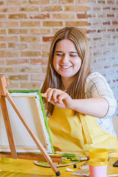 Vrouw met penseel schilderen op doek klaslokaal - Foto, afbeelding