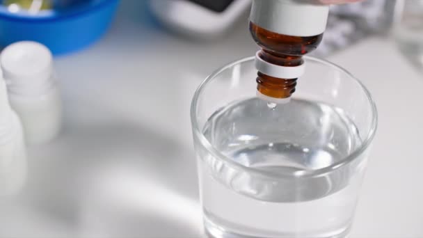 paineen normalisointi, nainen tippuu tippaa pullosta, jossa on annostelija läpinäkyvään vesilasiin, lähikuva-suunnitelma - Materiaali, video
