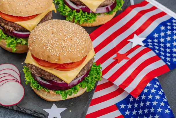 Homemade burgers. An American classic, traditional food for picnic, party or celebration Independence Day. Sauce, chips, sweet corn. Dark stone concrete background, close up - Foto, Imagem