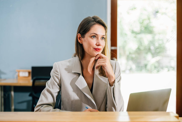 Profesionální podnikatelka používající notebook setkání a konverzace s partnery klienti on-line v moderní kanceláři, portrét ženy dívající se do kamery a sedí v kreativní kanceláři - Fotografie, Obrázek