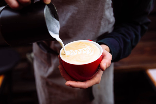 Barista wlewa świeże mleko do filiżanki kawy. Kwiat latte sztuki - Zdjęcie, obraz