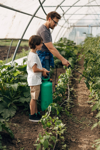 Side view of a boy working with his father in the vegetable garden. - Fotografie, Obrázek