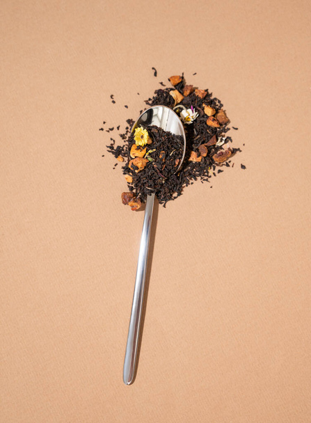Creative layout of dry scattered herbal tea from a spoon on a brown background with hard shadow.  Food and drink concept. Top view and copy space. - Foto, Bild