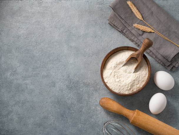 Ingredients for baking, wheat flour, eggs, rolling pin and kitchen textiles on a blue background. Homemade healthy food concept. Top view and copy space. - Foto, imagen