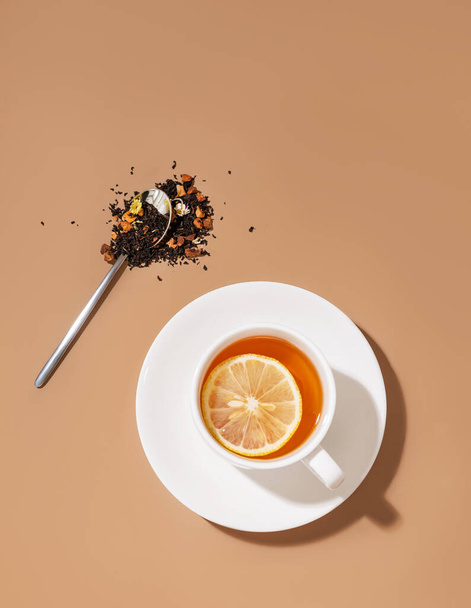 Ένα φλιτζάνι τσάι με λεμόνι σε καφέ φόντο με σκιά. Υγιές και αποτοξινωτικό ποτό. Κάτοψη και αντίγραφο χώρου. - Φωτογραφία, εικόνα