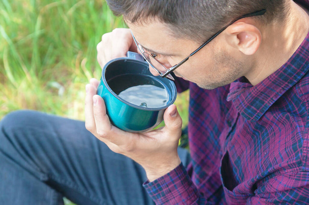 Mladý muž s čajem v ruce. Muž odpočívá venku. Odpočiň si v parku - Fotografie, Obrázek