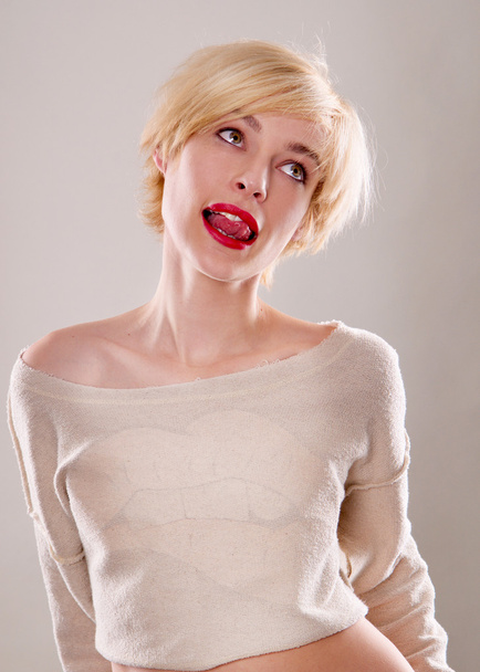 The blond woman with short hair and a beautiful smile with red lips isolated. Touches the lips - Photo, image