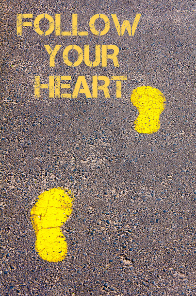 Yellow footsteps on sidewalk towards Follow your heart message - Photo, Image
