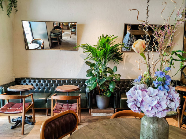 Topf mit frischen Blumen auf den Tischen im Vintage-Café, luxuriöses Interieur. Cafétisch, leer, keine Menschen. Romantisches Café, Innenblick. - Foto, Bild