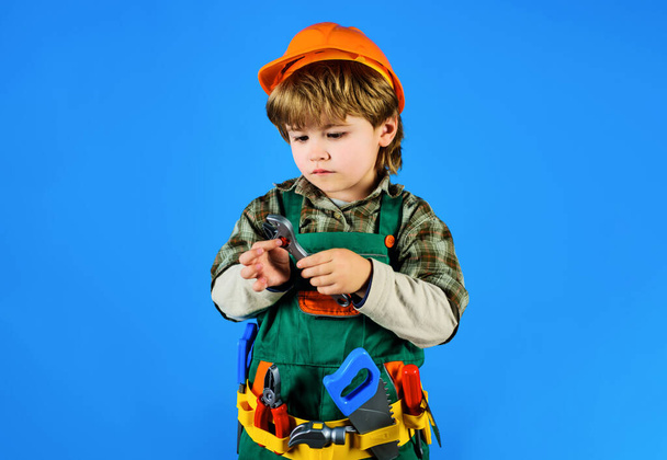 Kid repairman with toolbelt with wrench. Little kid in builder uniform with spanner. Child game. Boy construction worker in helmet with adjustable spanner. Tools for building. Work with tools. Repair - Photo, image