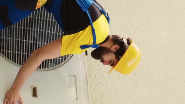Vertical video Expert technician contracted to repair broken air conditioner, dismantling condenser front coil panel to check faulty blower fan. Wireman opening hvac system to check for bad wiring - Footage, Video
