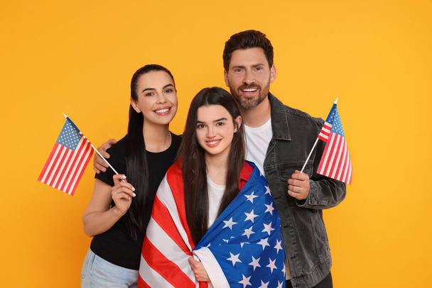 4. Juli - Unabhängigkeitstag der USA. Glückliche Familie mit amerikanischen Flaggen auf gelbem Hintergrund - Foto, Bild
