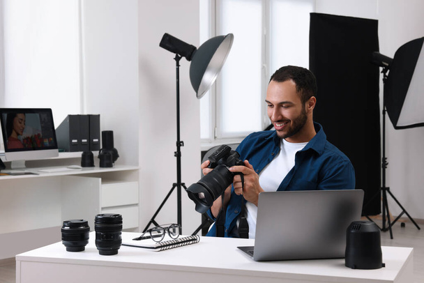 Young professional photographer with camera in modern photo studio, space for text - Foto, immagini