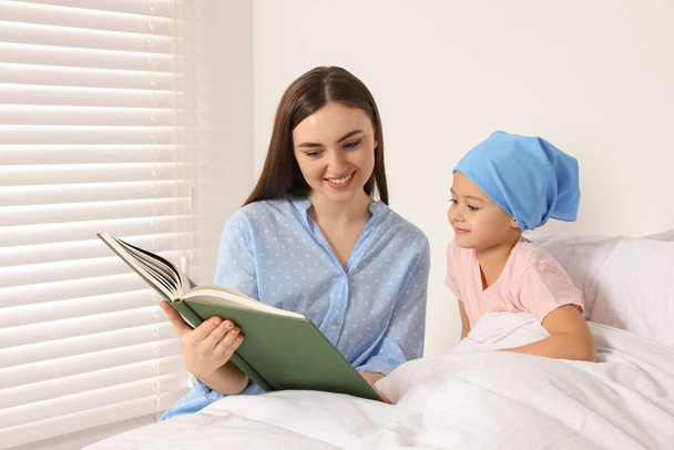 Cáncer infantil. Madre e hija leyendo libro en el hospital - Foto, imagen