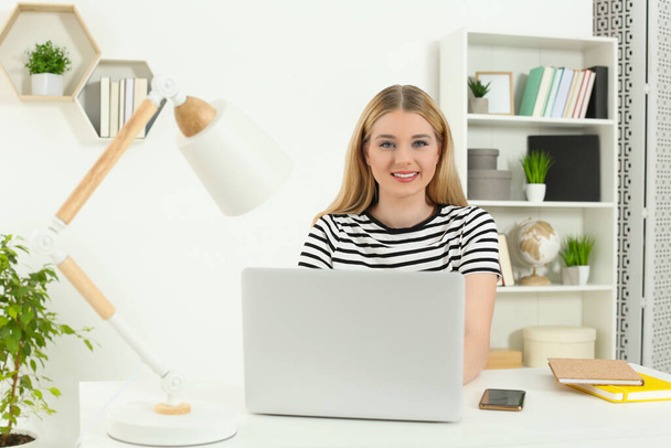 Lugar de trabajo. Retrato de mujer cerca de la computadora portátil en el escritorio blanco en la habitación - Foto, imagen