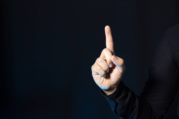 A business person showing a finger up. Hand gesture isolated on a black background. Point up. - Photo, image