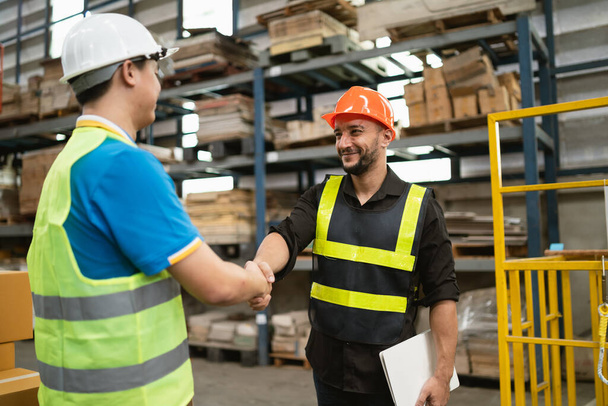 Industrial warehouse manager engineer worker in safety suite handshake celebrate successful or deal commitment. Logistics , supply chain and warehouse business.Teamwork unity under view concept. - Photo, Image