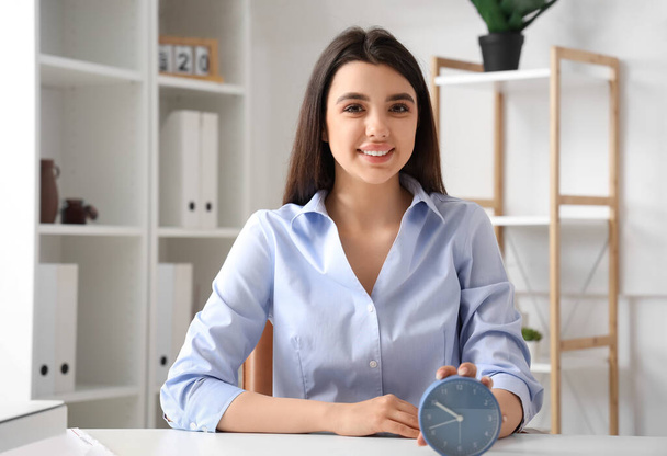 Businesswoman with alarm clock in office. Time management concept - Фото, изображение