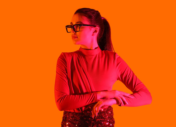 Módní mladá žena nosí brýle na oranžovém pozadí - Fotografie, Obrázek
