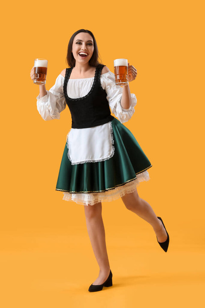 Krásná Oktoberfest servírka s pivem tanec na žlutém pozadí - Fotografie, Obrázek