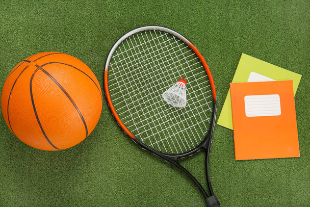 Badminton shuttlecock met racket, bal en notebooks op kleur achtergrond - Foto, afbeelding