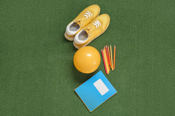 Sneakers with ball and stationery on color background - Valokuva, kuva