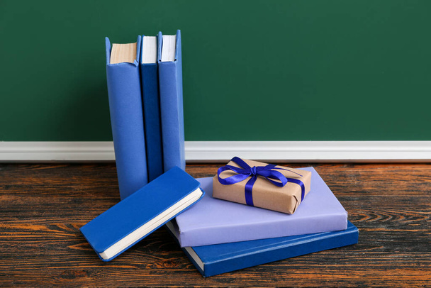 Caja de regalo con diferentes libros sobre mesa de madera marrón en el aula - Foto, imagen