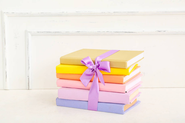 Стек барвистих книг з бузковою стрічкою на білому столі - Фото, зображення