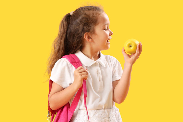 Little schoolgirl with apple on  yellow background - Foto, immagini