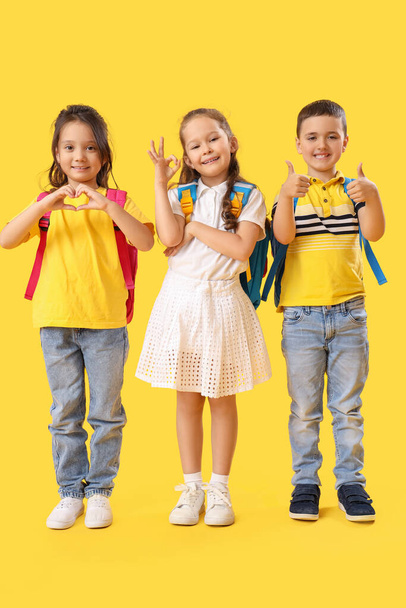 Petits écoliers montrant des gestes différents sur fond jaune - Photo, image