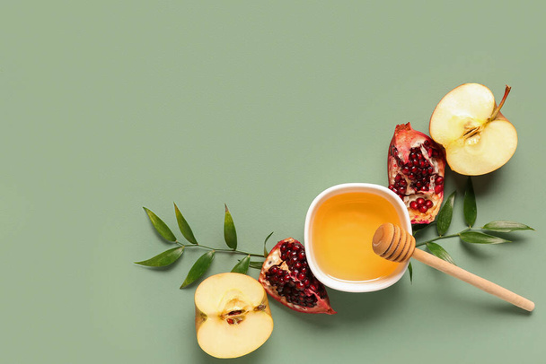 Bowl of honey, pomegranate and apple for Rosh Hashanah celebration (Jewish New Year) on green background - Fotó, kép