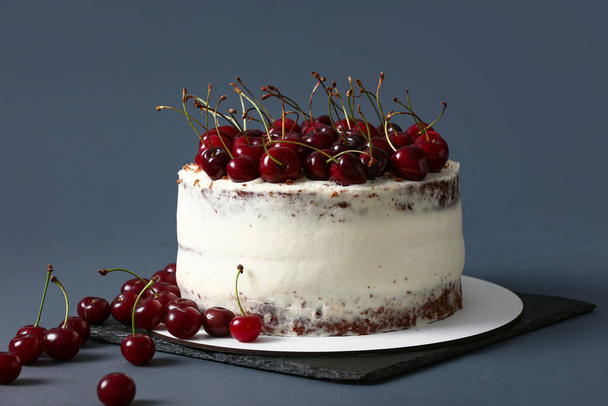 Board with tasty cherry cake on dark background - Foto, imagen