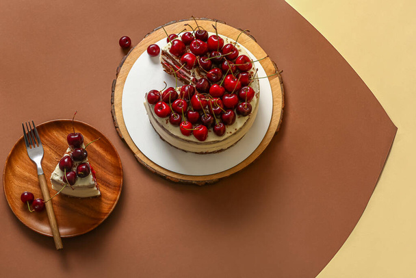 Plate and wooden board with tasty cherry cake on color background - Photo, Image