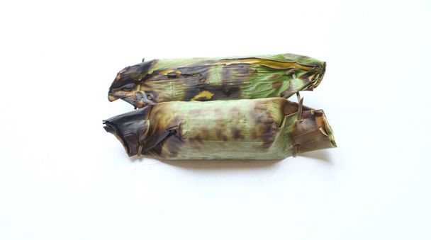 Comida tradicional de tailândia feita a partir de arroz pegajoso envolto em folhas de banana com recheio de taro e banana e grelhado em carvão isolado tartaruga em um fundo branco - Foto, Imagem