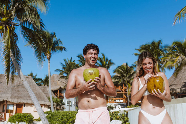 Spanisches junges Paar hält eine Kokosnuss in der Hand und amüsiert sich am karibischen Strand im Urlaub oder Urlaub in Mexiko Lateinamerika - Foto, Bild