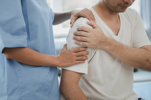 A physiotherapist doing physiotherapy for a patient in a hospital room, physiotherapy helps to recover from illness by moving the body and muscles. The concept of treating illnesses with physical therapy. - Φωτογραφία, εικόνα