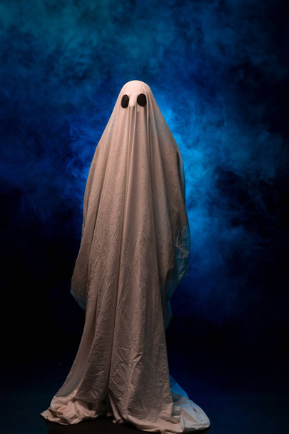 Spaventoso fantasma coperto di lenzuolo su uno sfondo scuro nel fumo. Poster di Halloween. Copia spazio - Foto, immagini