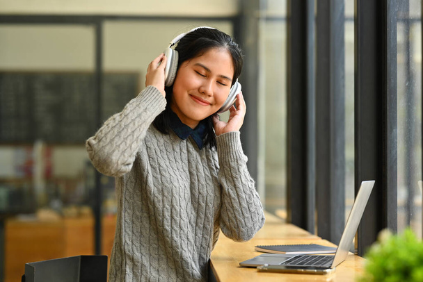 Relaxed young woman listening music on headphones with closed eyes, enjoying music. - Foto, Imagen