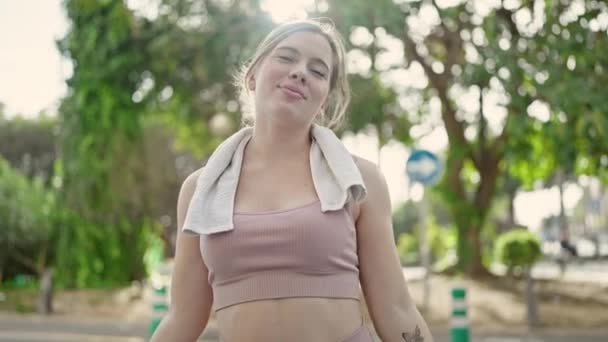 jonge blonde vrouw glimlachen zelfverzekerd dragen sportkleding in park - Video