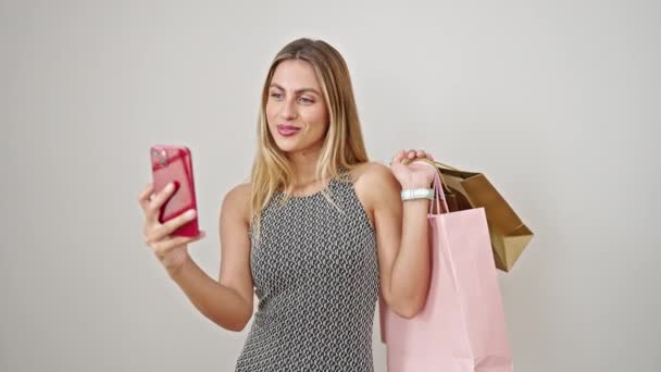 Jonge blonde vrouw met boodschappentassen maken selfie door smartphone over geïsoleerde witte achtergrond - Video