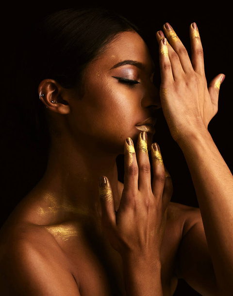 Woman, gold makeup and studio for paint, beauty or body art for creativity, design and black background. Girl, model and skin with metallic texture, pattern or color for cosmetics with dark aesthetic. - Foto, Bild