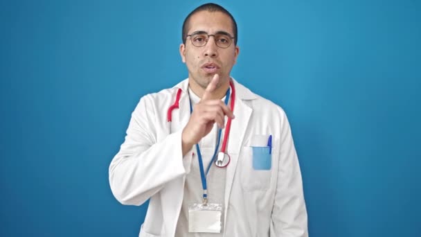 Joven médico hispano pidiendo silencio sobre fondo azul aislado - Metraje, vídeo