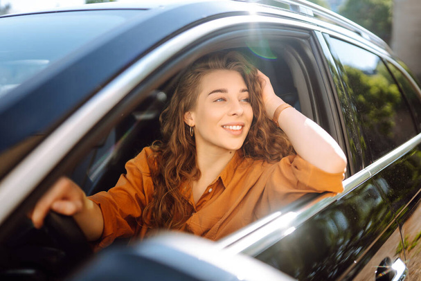 Smiling woman driving a car. Young traveler driving. Car travel, lifestyle concept. - Fotó, kép