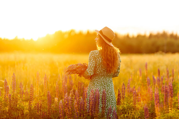 Beautiful  woman in style dress on blooming fragrant lavender fields. Nature, vacation, relax and lifestyle - Photo, Image