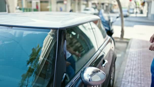 Joven hombre hispano sonriendo confiado abriendo la puerta de coche en la calle - Metraje, vídeo