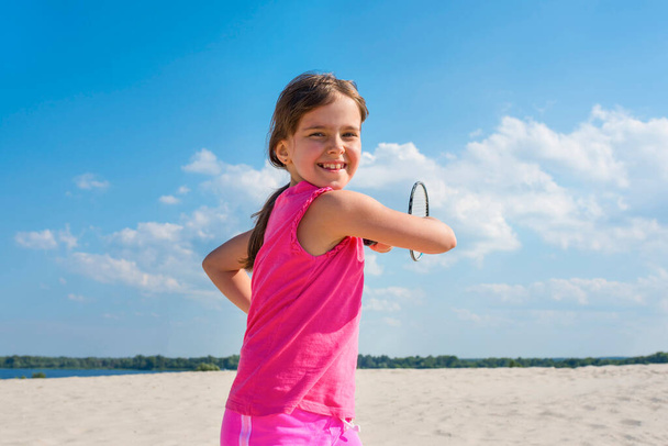 Outdoor portrait of happy girl playing beach badminton on the beach. Summer vacation, sports, lifestyle - Foto, Imagen