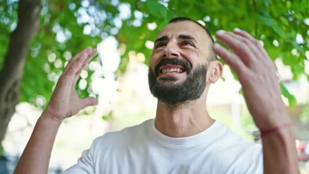Jeune homme hispanique regardant le ciel avec un geste gagnant au parc - Séquence, vidéo
