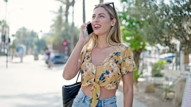 Mujer rubia joven sonriendo confiado hablando en el teléfono inteligente en el parque - Metraje, vídeo