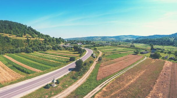 Aerial view of the countryside, highway, and cultivated fields on the hills - Фото, изображение