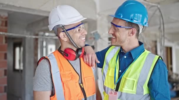 Δύο άνδρες οικοδόμοι χαμογελώντας σίγουροι στέκεται μαζί στο εργοτάξιο - Πλάνα, βίντεο